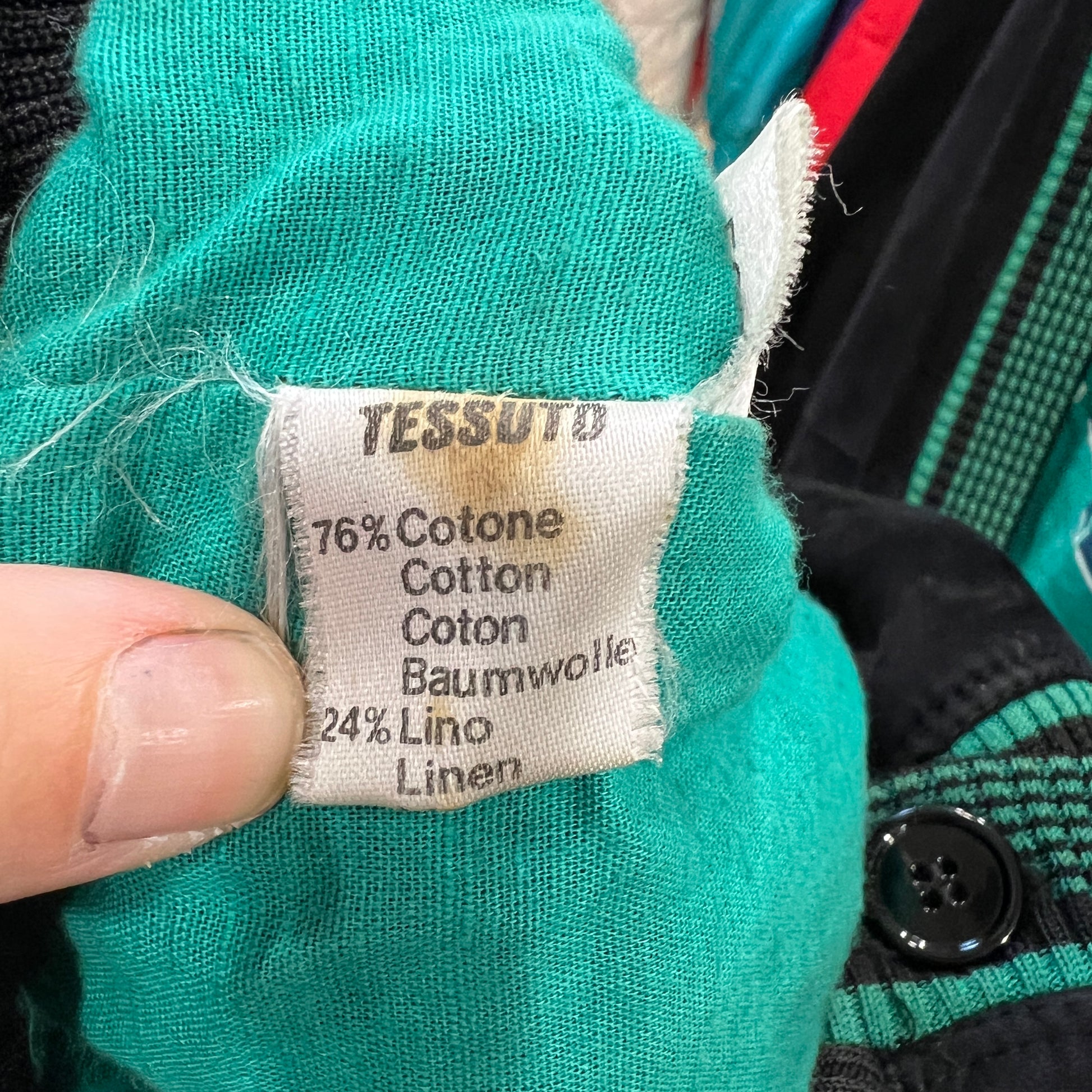 Clothing label on teal fabric with text indicating material composition