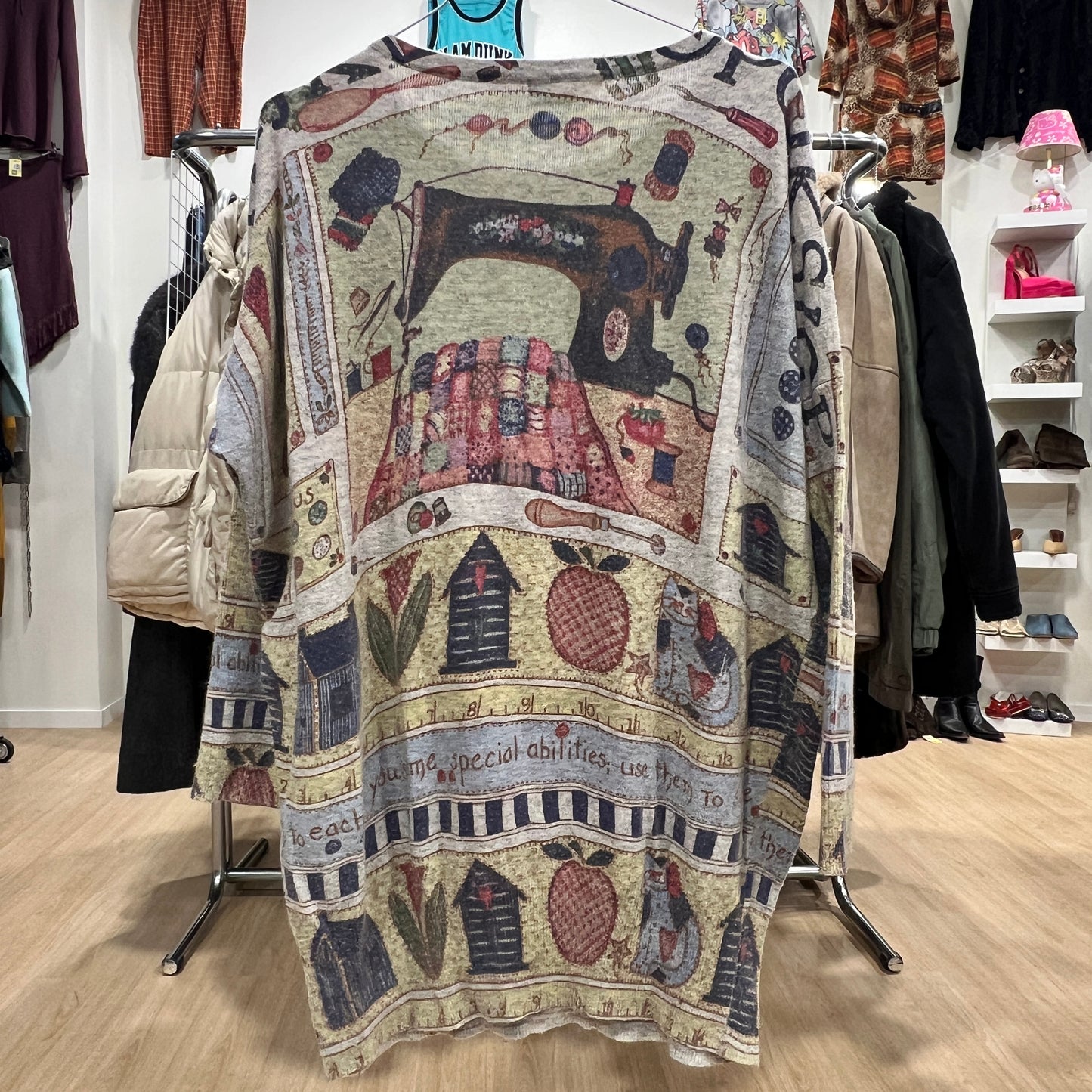 Decorative sweater with sewing machine design hanging on a rack in a store