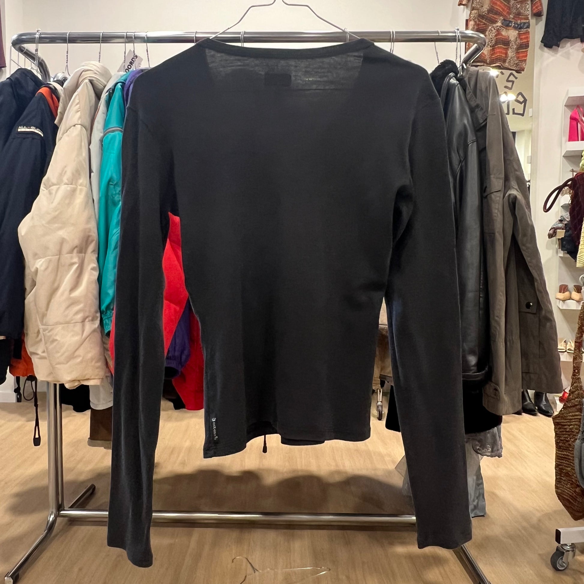 Black long-sleeve shirt on a hanger with other clothing in the background