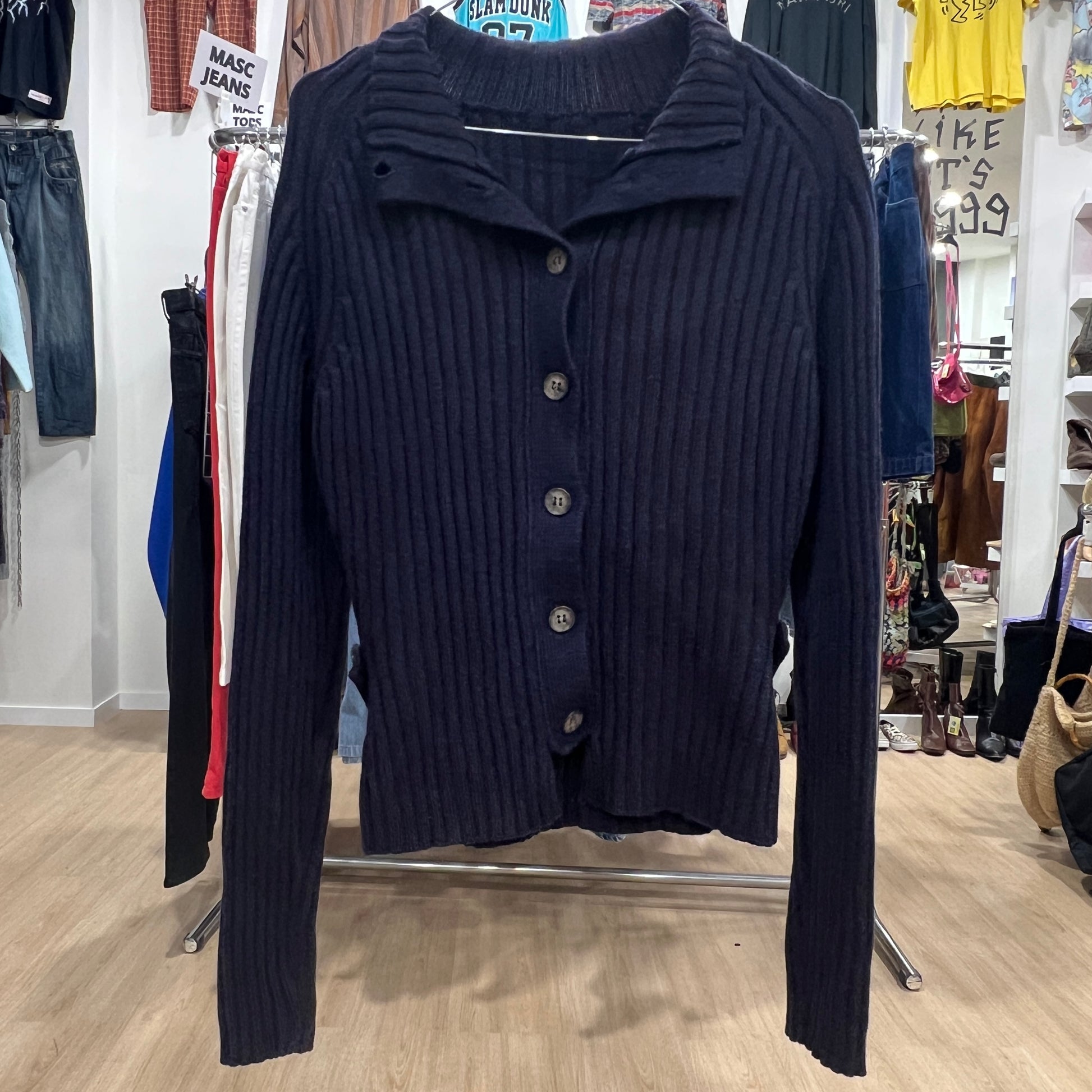 Navy blue ribbed sweater on a rack in a store setting