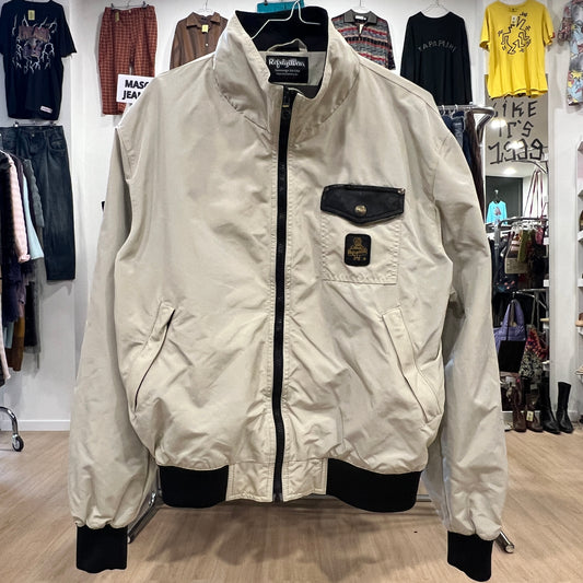 Front view of a beige vintage jacket with black zipper, black chest pocket, and ribbed cuffs and hem, displayed on a hanger ins
