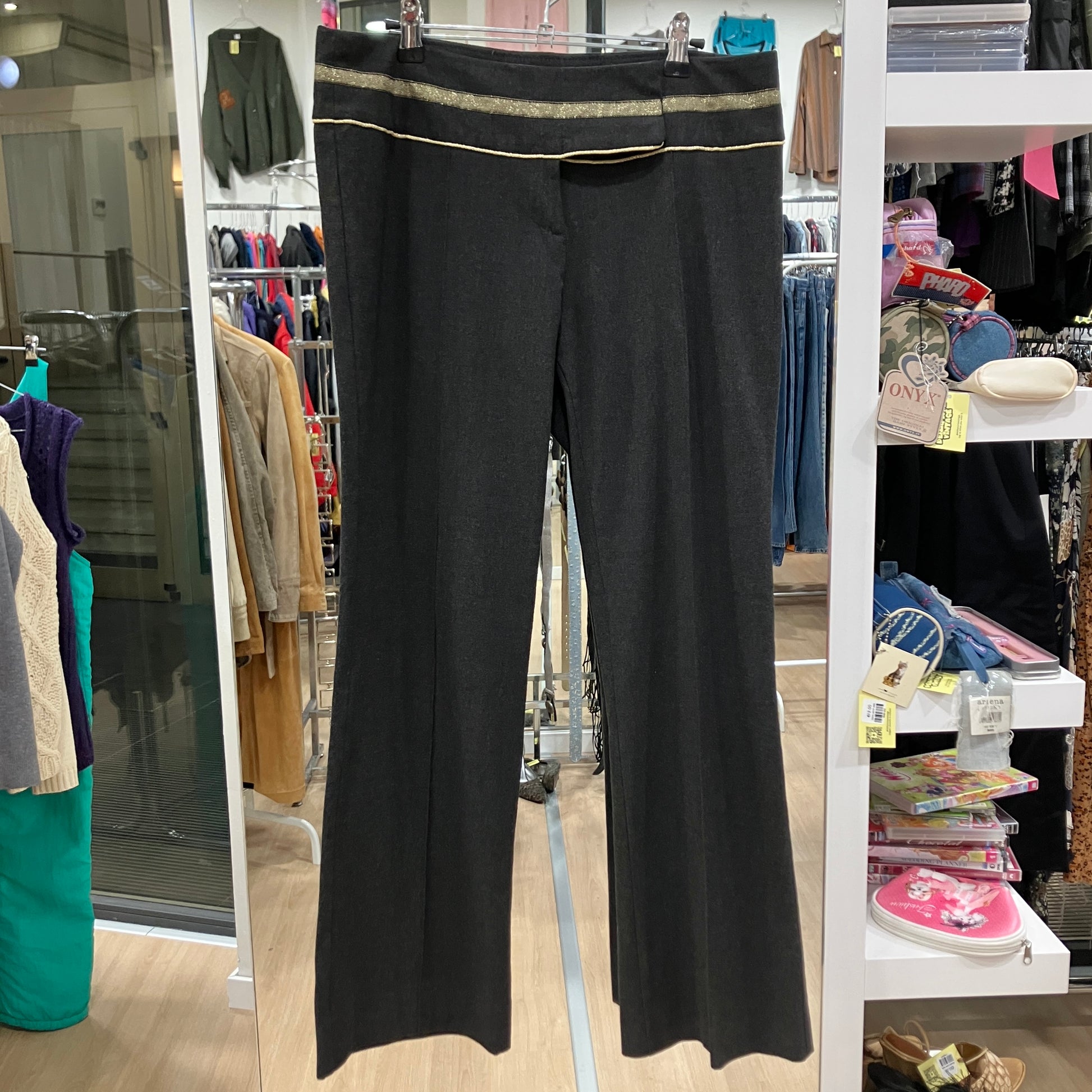 Black pants with gold trim hanging in a store
