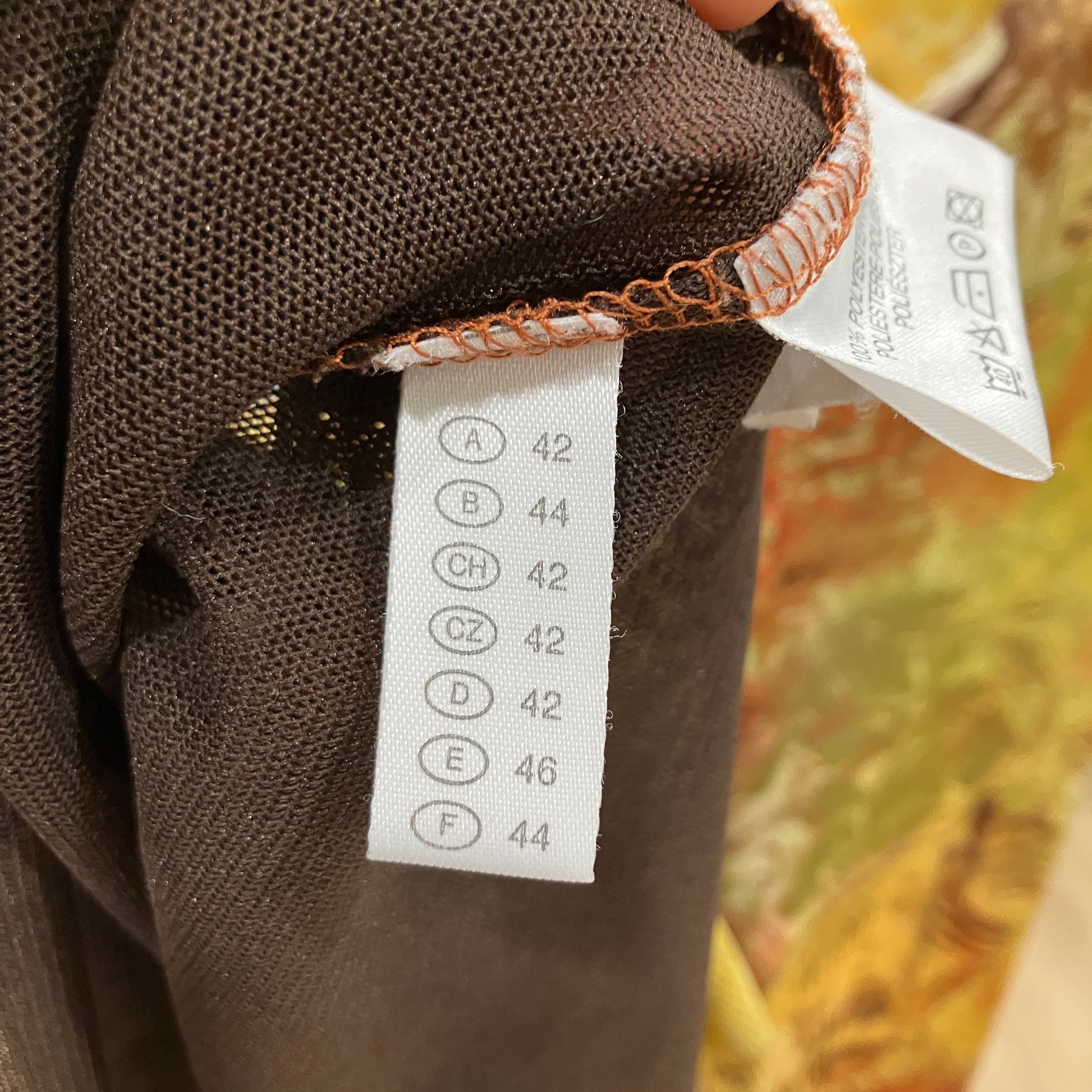 Close-up of a brown fabric garment with a size label on a blurred background