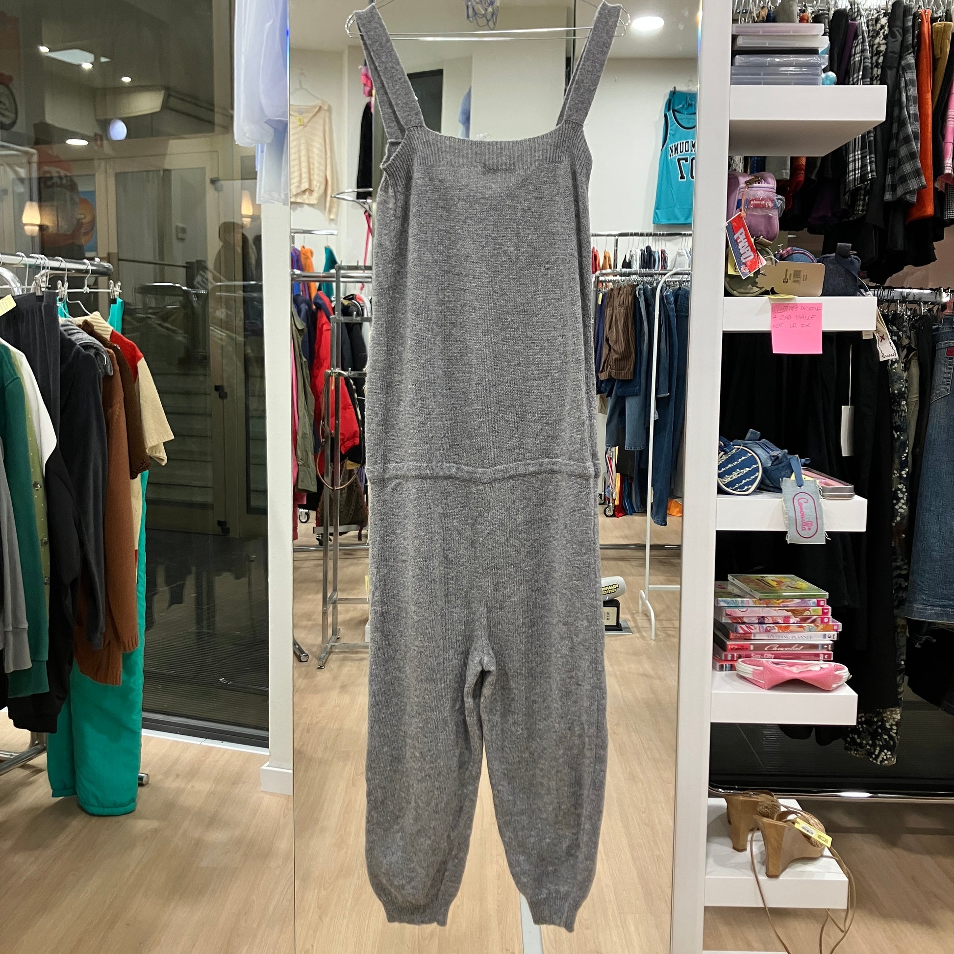 Gray jumpsuit displayed in a store with racks of clothes in the background