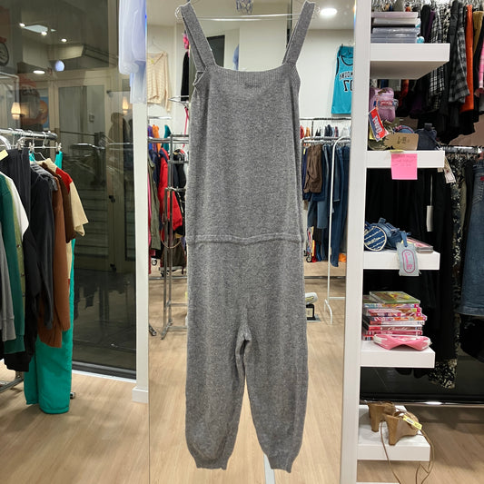 Gray jumpsuit displayed in a store with racks of clothes in the background