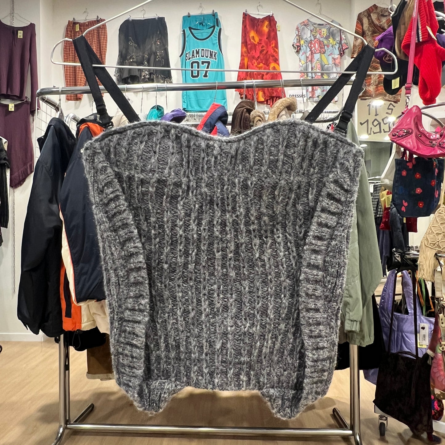 Gray knitted top on a clothing rack with various garments in the background