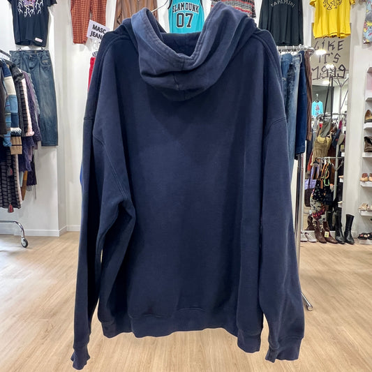 Navy blue hoodie displayed in a store with clothing racks in the background