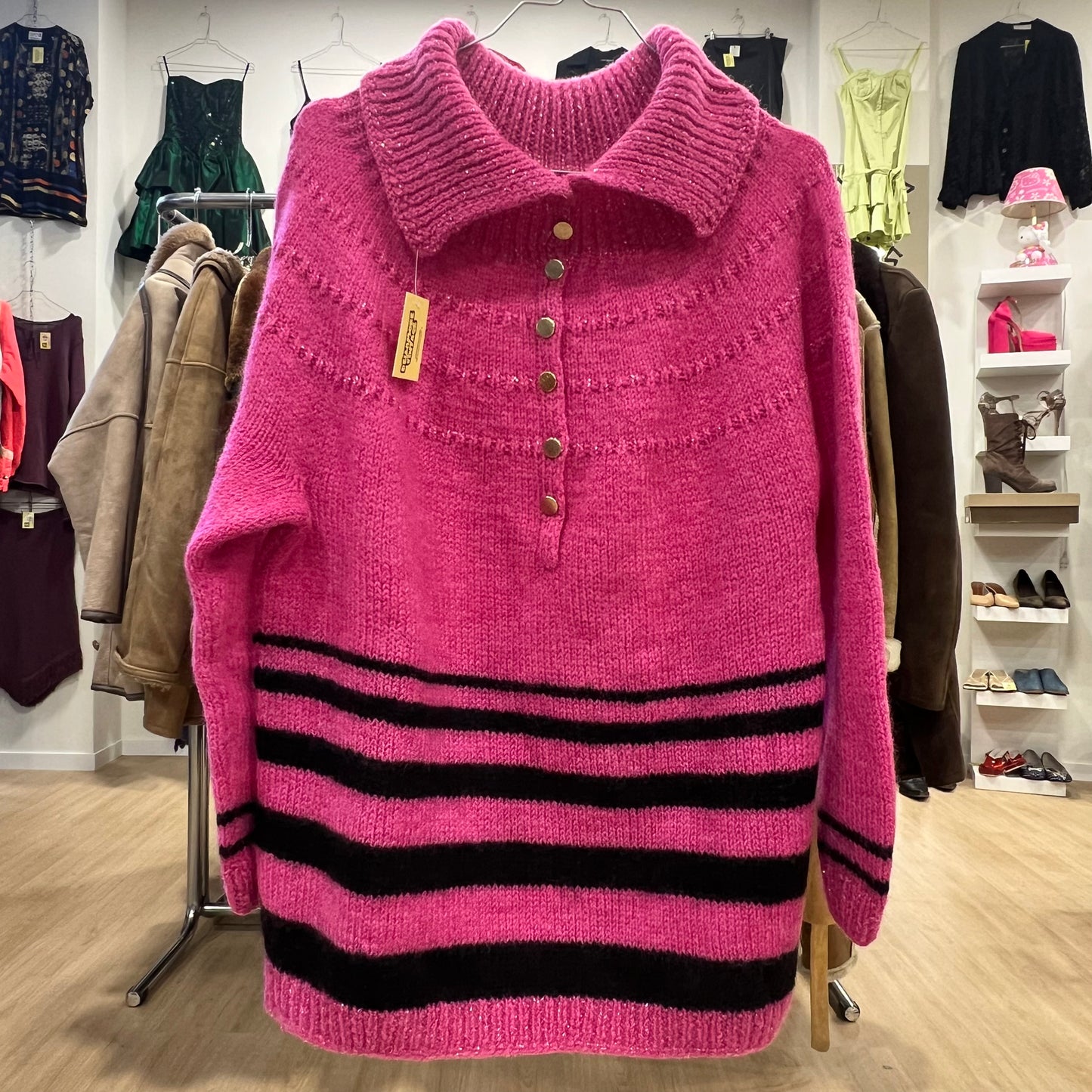 Pink sweater with black stripes on a rack in a store setting