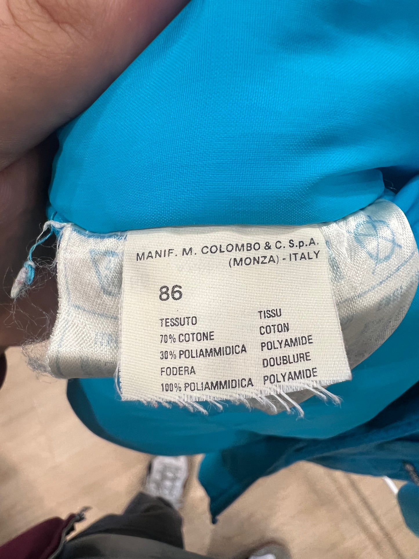 Clothing label with brand and material information on a blue garment