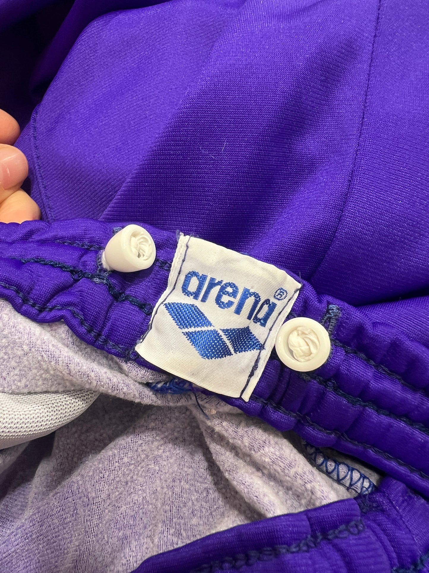 Close-up of a purple pants with Arena logo and branding