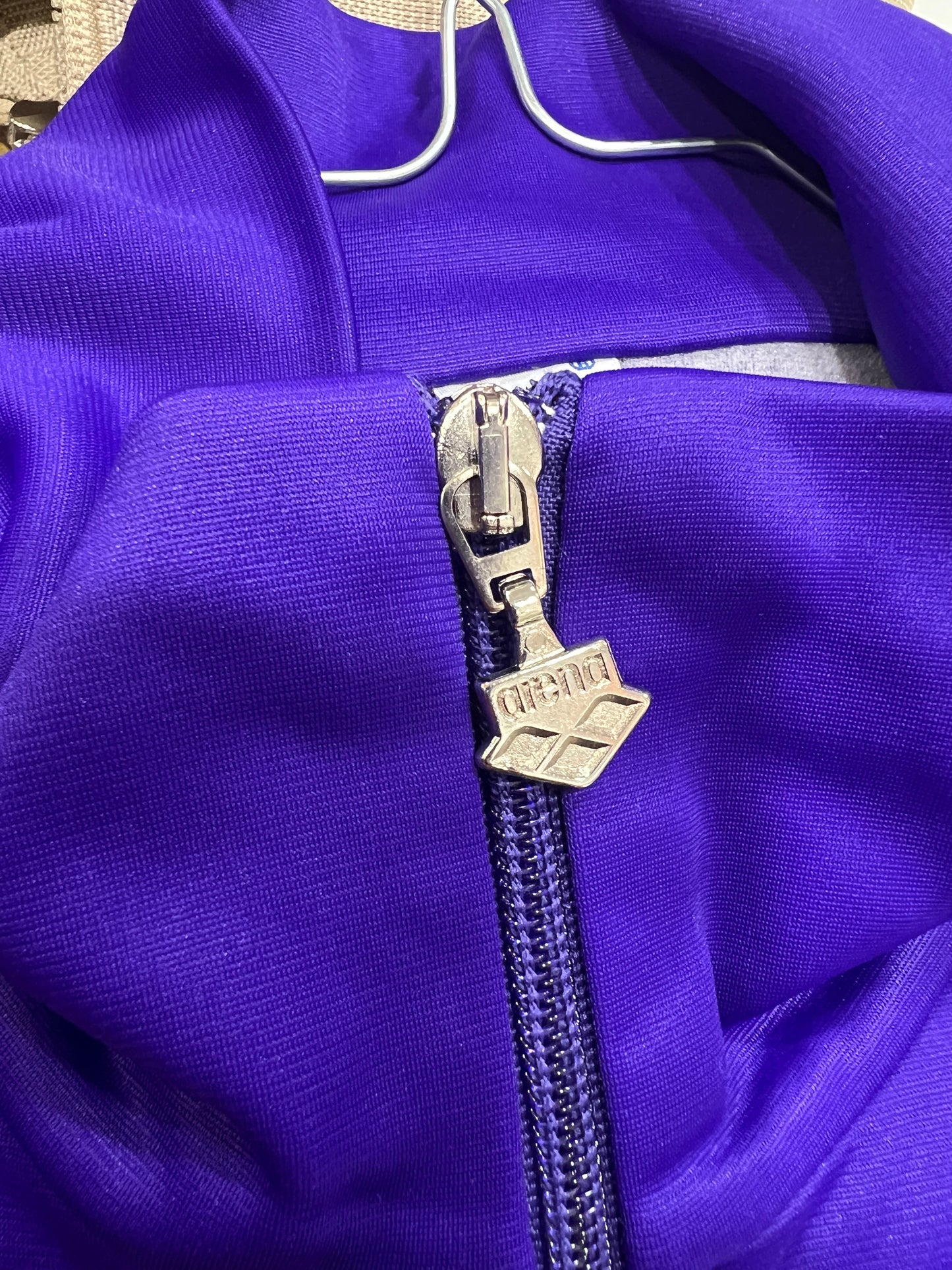 Close-up of a purple garment with a zipper and arena logo