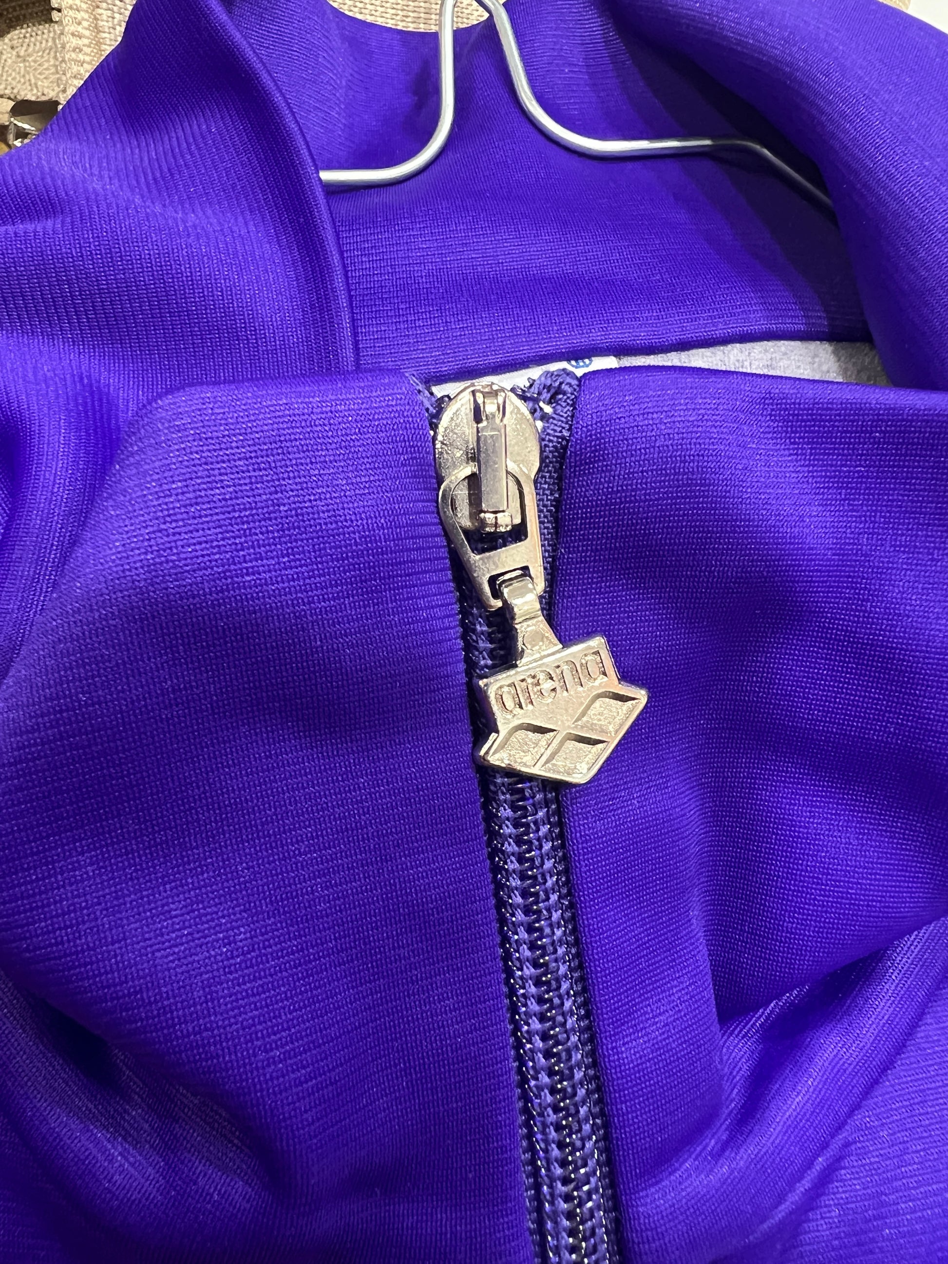 Close-up of a purple garment with a zipper and arena logo