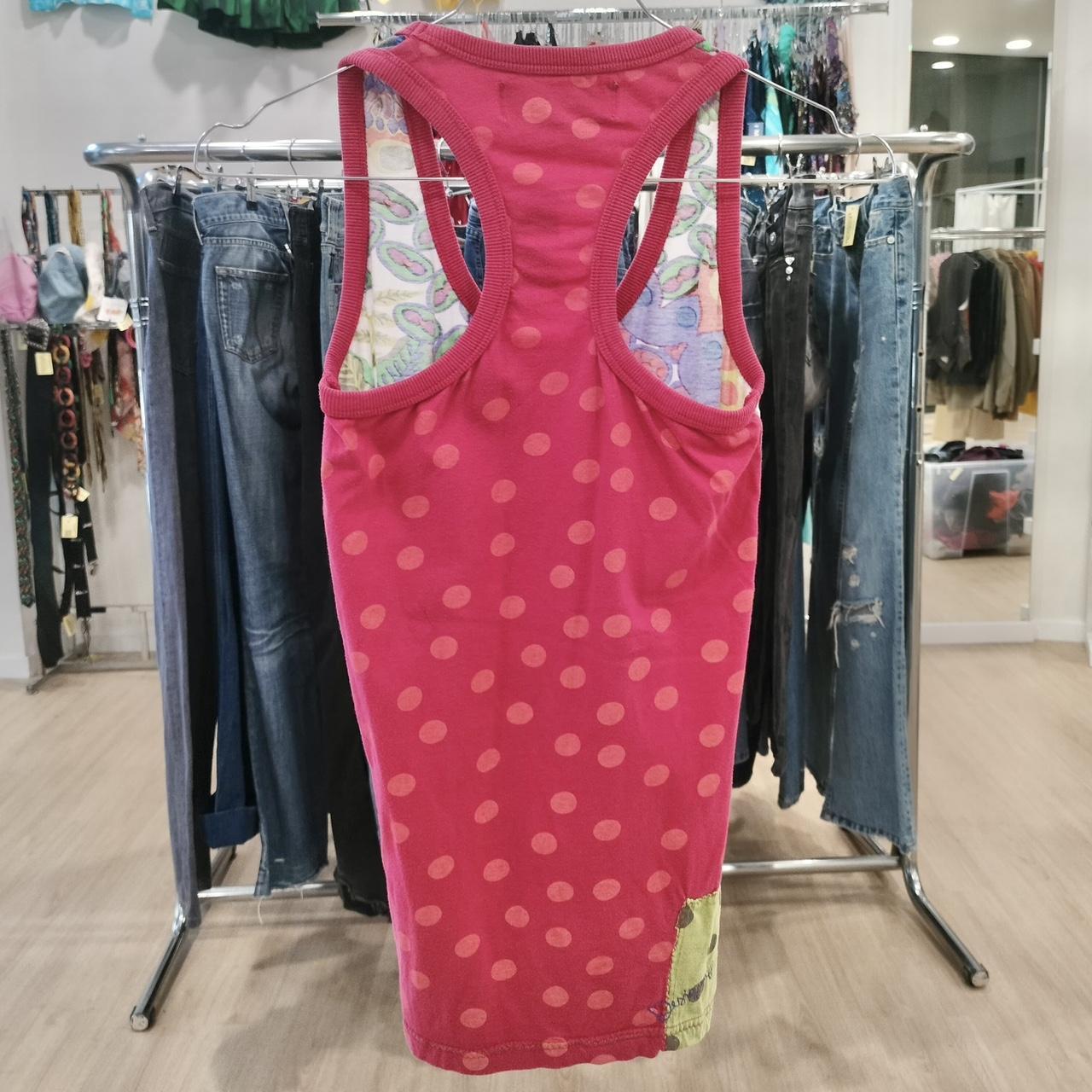Pink tank top on a rack with jeans in a store setting