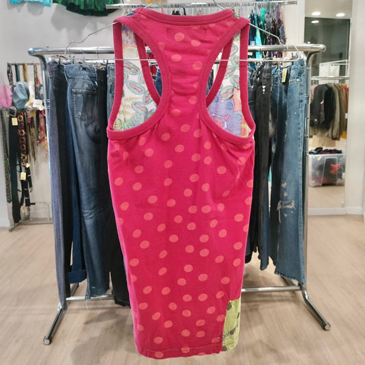 Pink tank top on a rack with jeans in a store setting