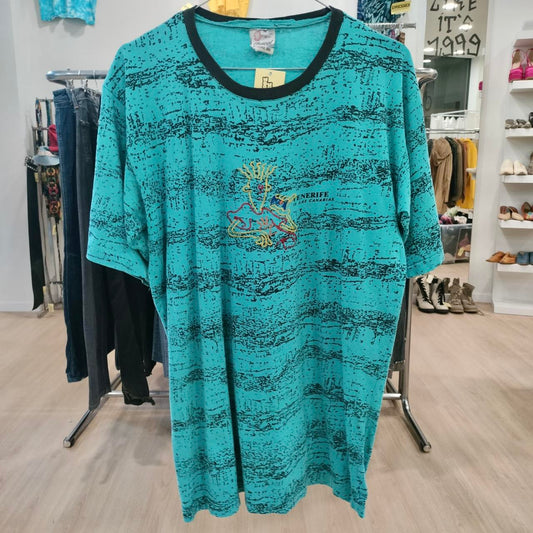 Teal dress with black accents on a rack in a store setting