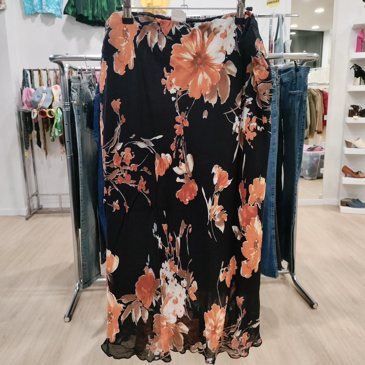 Black midi skirt with orange floral print displayed in a second hand fashion boutique