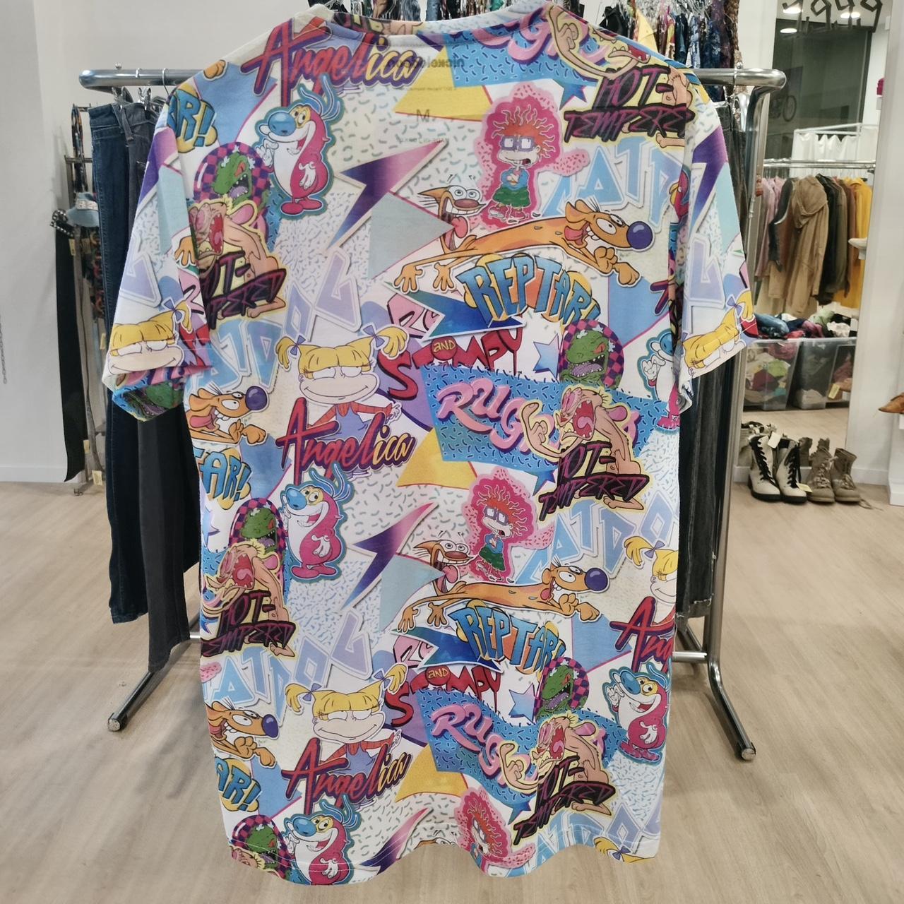 Colorful graphic t-shirt with various designs and text on a rack in a store
