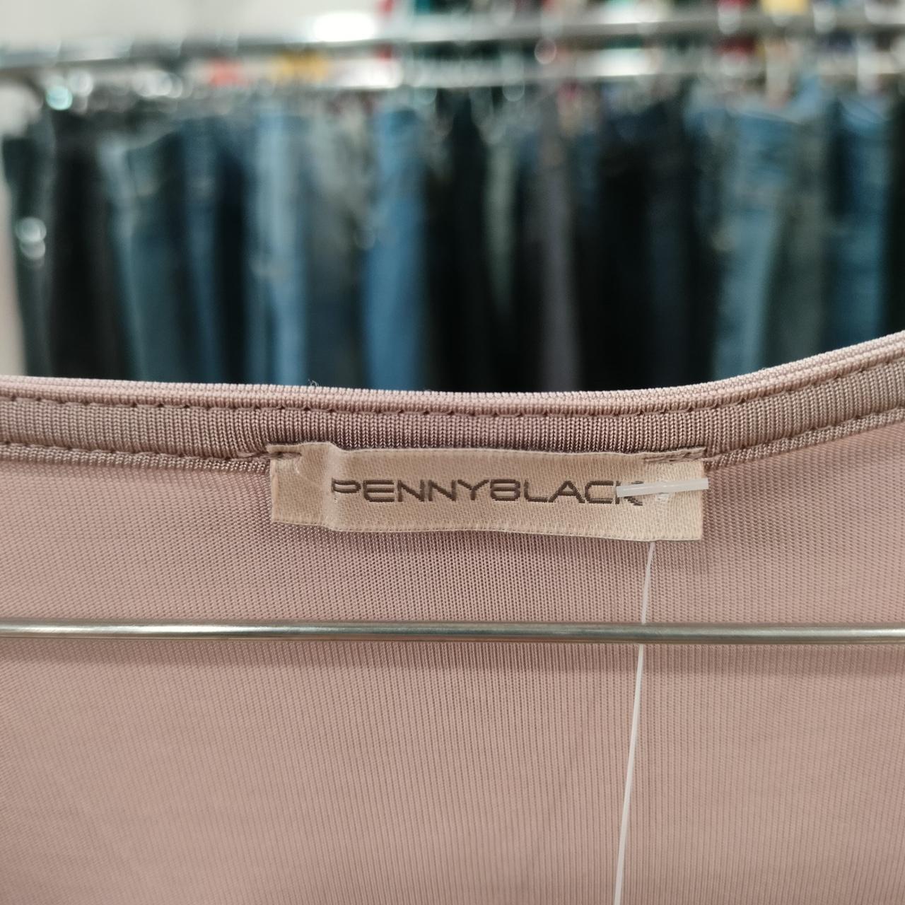 Close-up of a brown garment with a 'Pennyblack' label, blurred jeans in the background