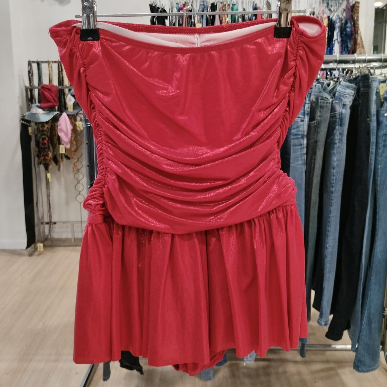 Red strapless dress hanging on a rack in a store setting