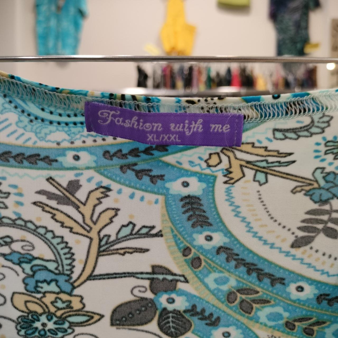 Close-up of a patterned fabric with a 'Fashion with me' tag in the background
