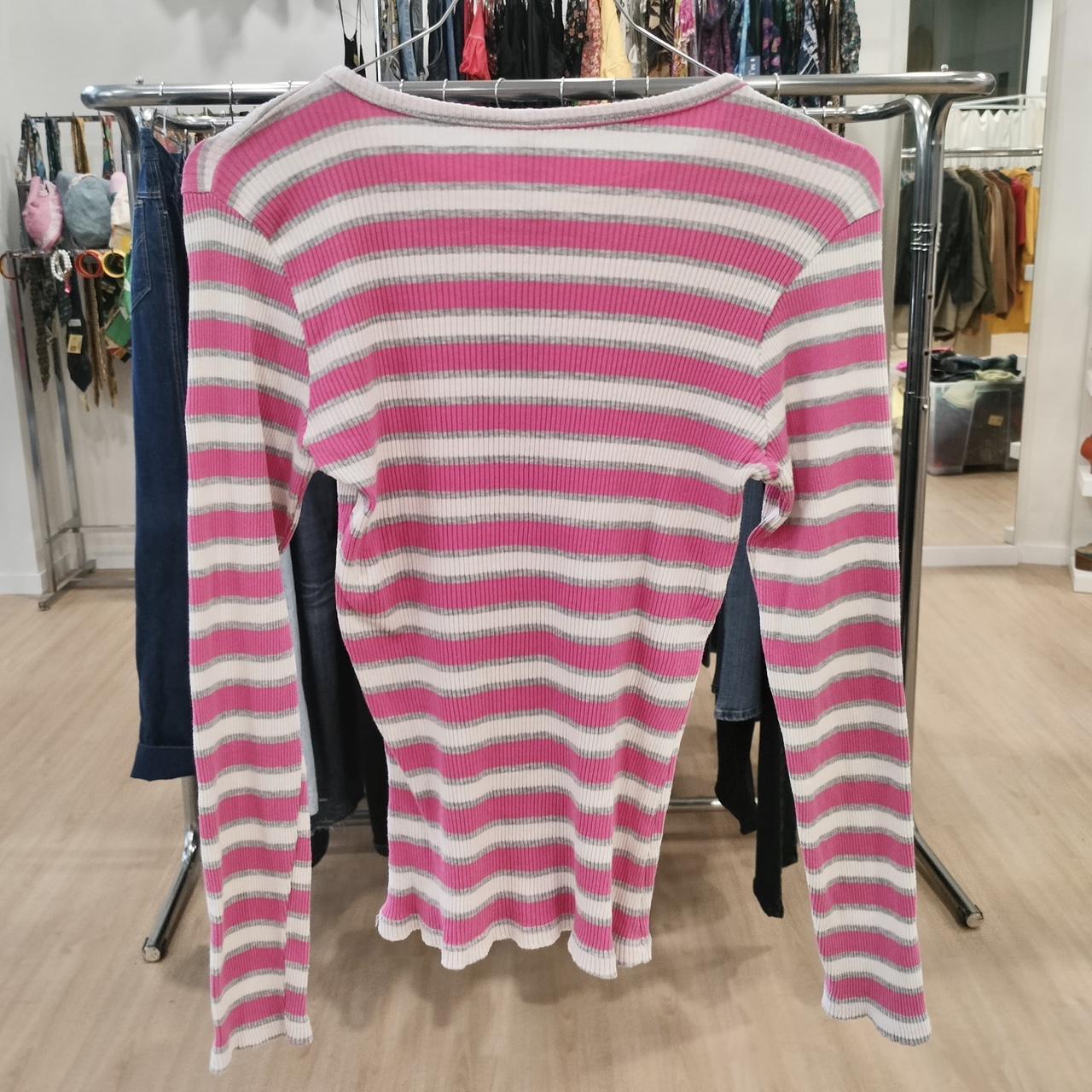 Pink and white striped long sleeve ribbed shirt hanging in a second hand fashion store
