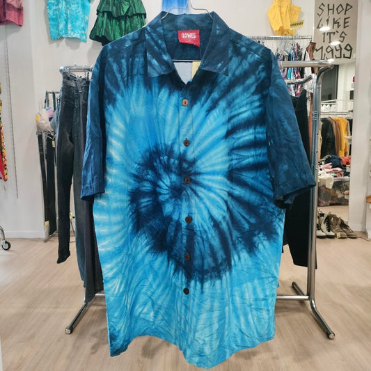 Blue tie-dye button-up shirt with short sleeves hanging in second hand clothing store