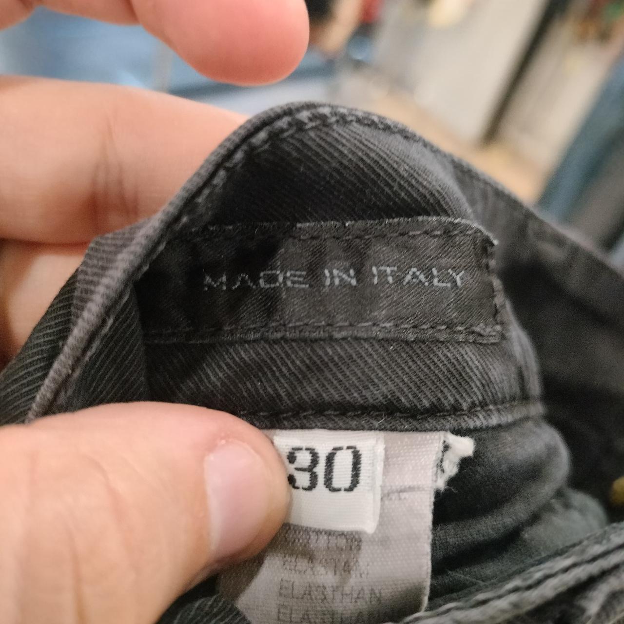 Close-up of 'Made in Italy' label and size 30 tag on black denim jeans