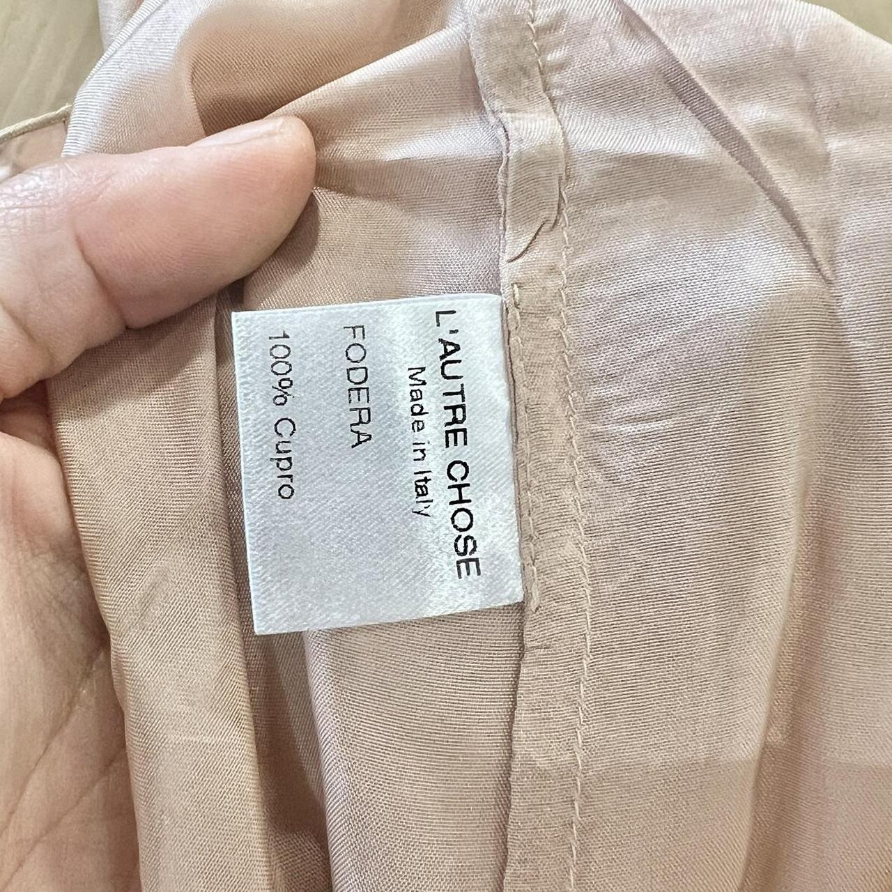 Close-up of a fabric label on a beige garment with 'L'Autre Chose' branding