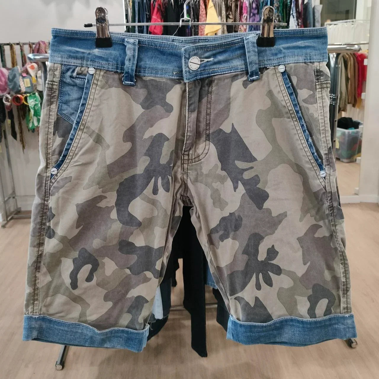 Camouflage print shorts with denim trim displayed in a sustainable second hand fashion store