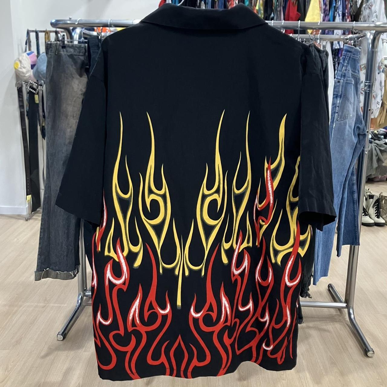 Black shirt with red and yellow flame design on a clothing rack