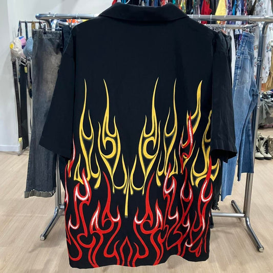 Black shirt with red and yellow flame design on a clothing rack
