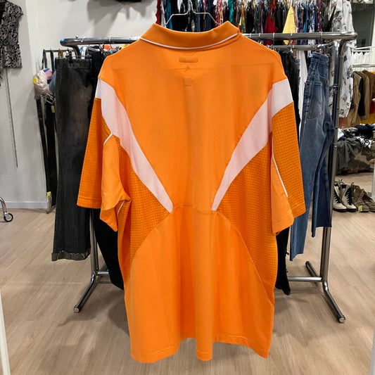 Orange polo shirt with white accents on a rack in a store setting