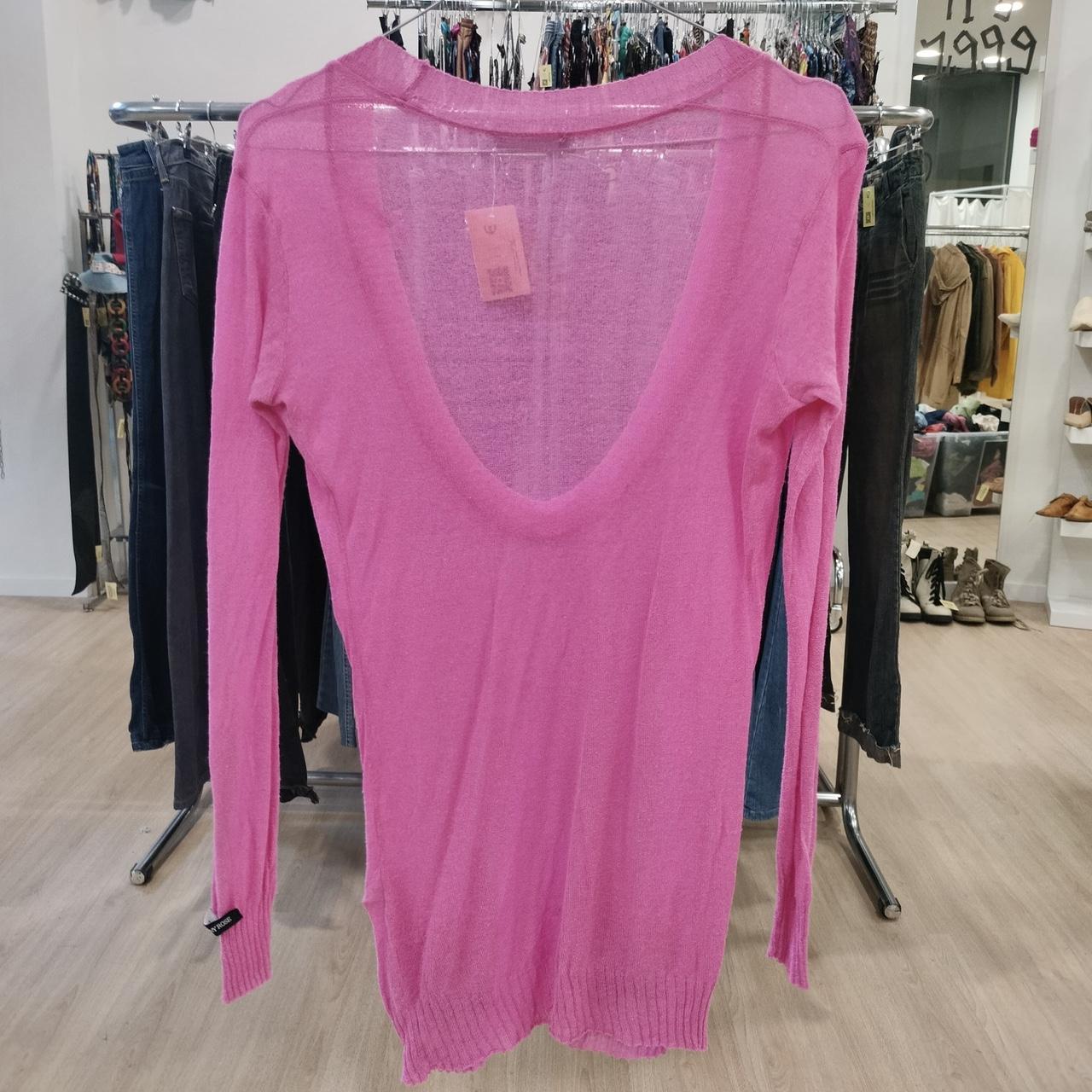 Pink sweater on a rack in a store setting with a price tag