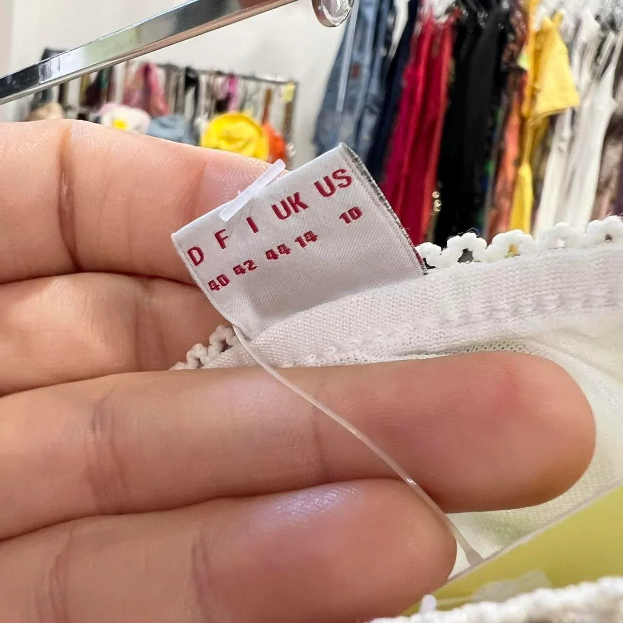 Close-up of a clothing size tag on a white garment, second hand fashion shop background