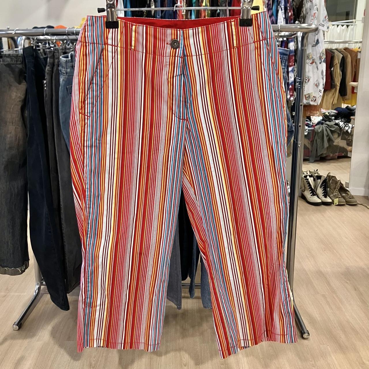 Colorful striped pants with red, orange, blue, and white vertical lines hanging in a store