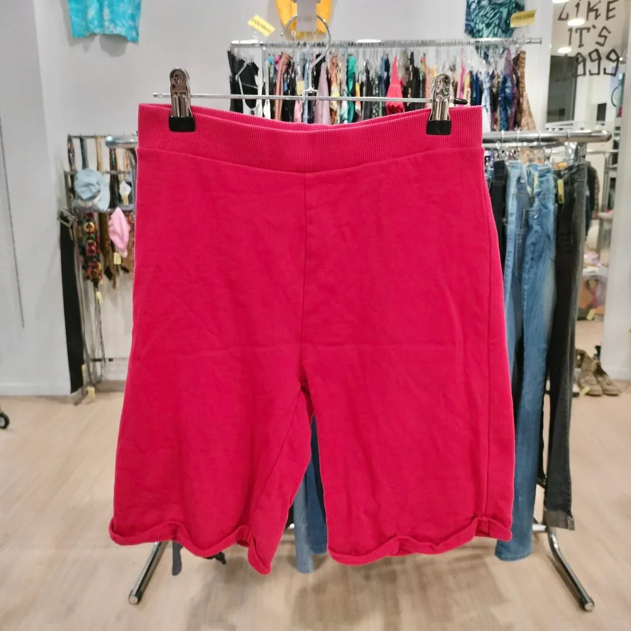 Bright pink cotton shorts hanging on a rack in a second hand fashion store