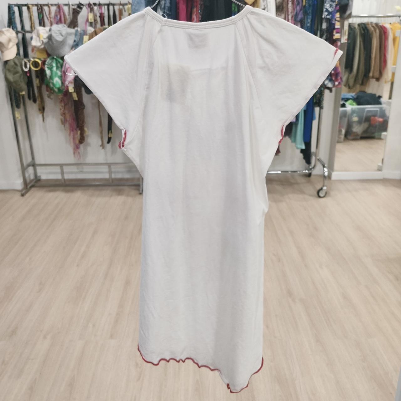 White short-sleeve dress with red trim on hanger in second hand clothing shop