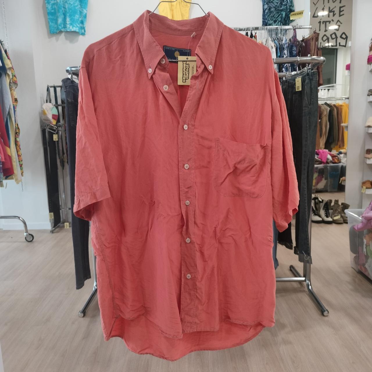 Red shirt on a hanger in a store setting with various clothing items in the background