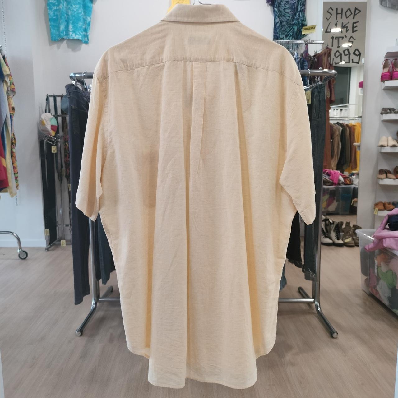 Beige shirt on a mannequin in a store setting with various items in the background