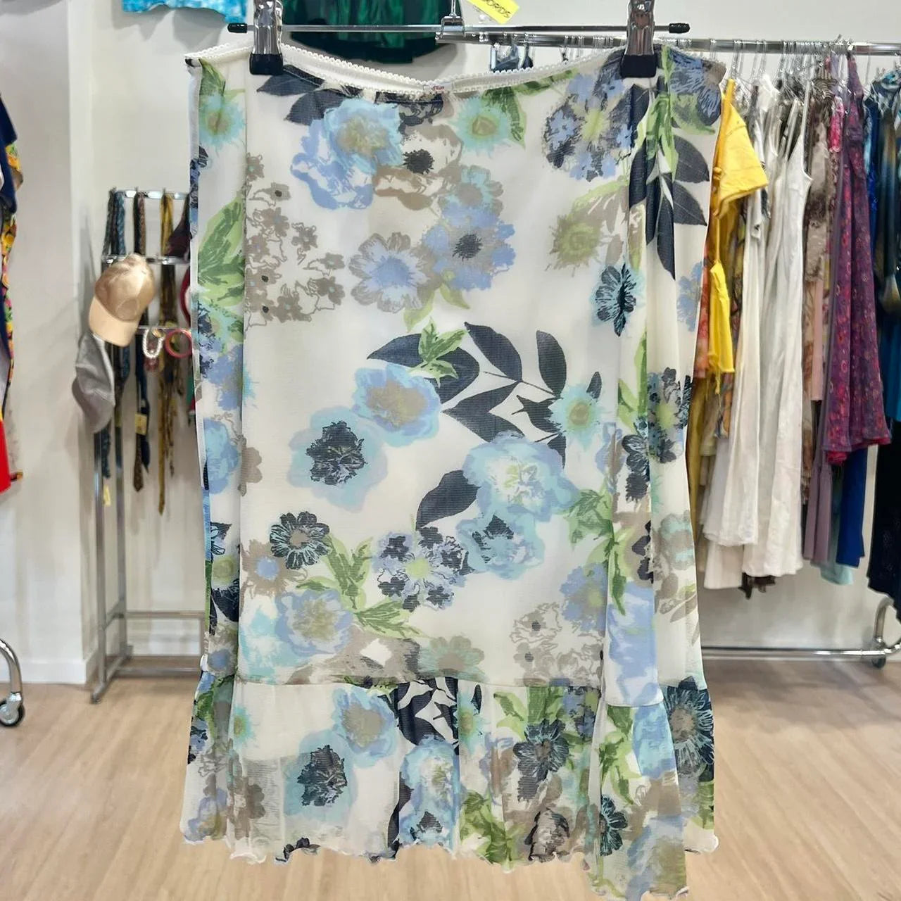 Sheer floral print skirt with blue and green flowers on display in a second hand clothing store