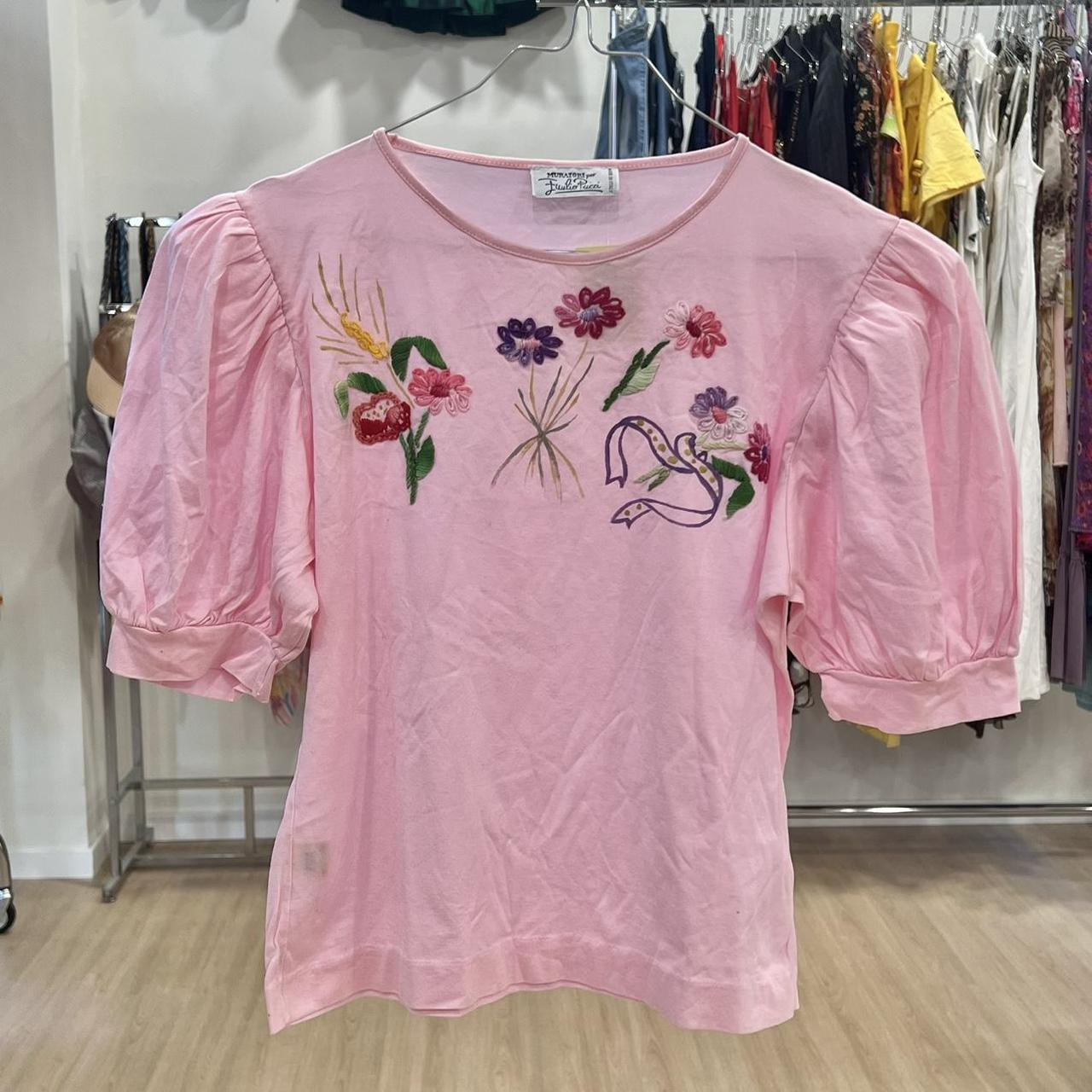 Pink blouse with floral embroidery on a rack in a store