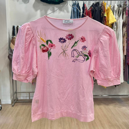 Pink blouse with floral embroidery on a rack in a store