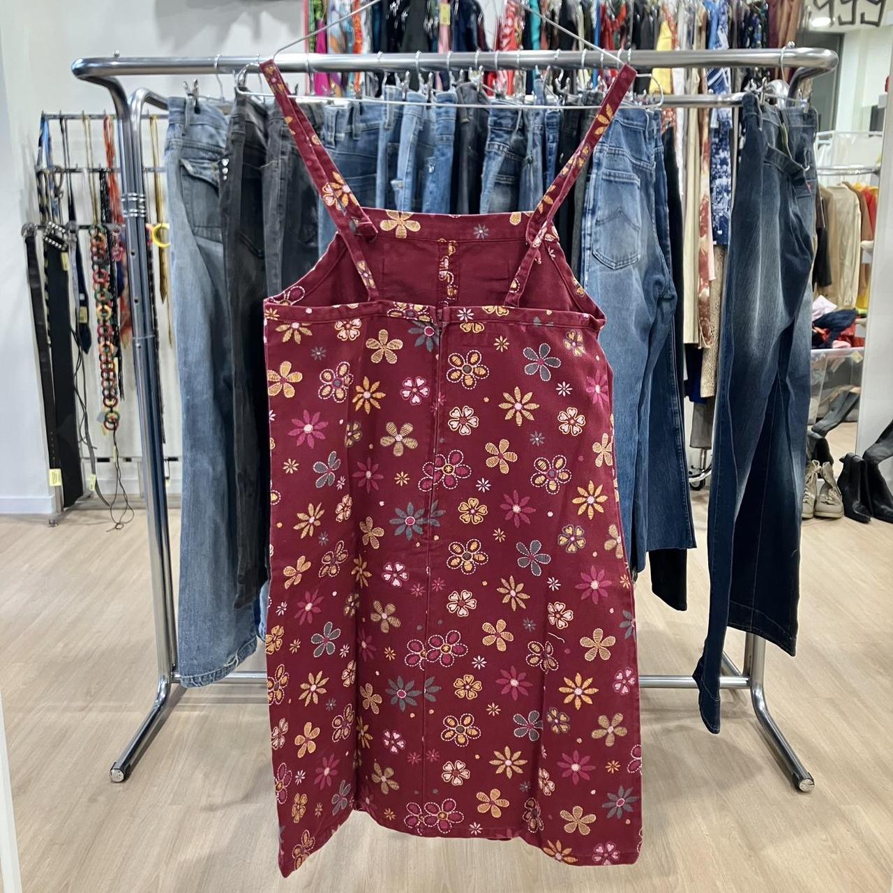 Red floral print sleeveless dress on hanger in a second hand clothing store