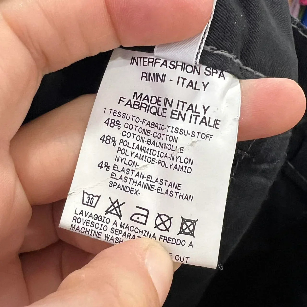 Close-up of a second hand fashion clothing label showing fabric content and care instructions.