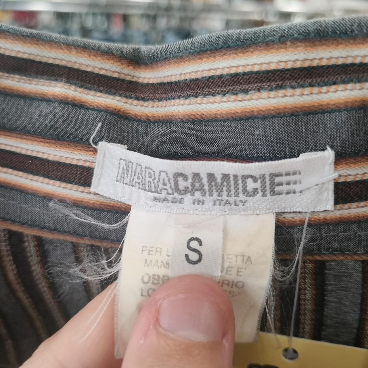 Close-up of a striped fabric with a Nara Camicie label on a blurred background