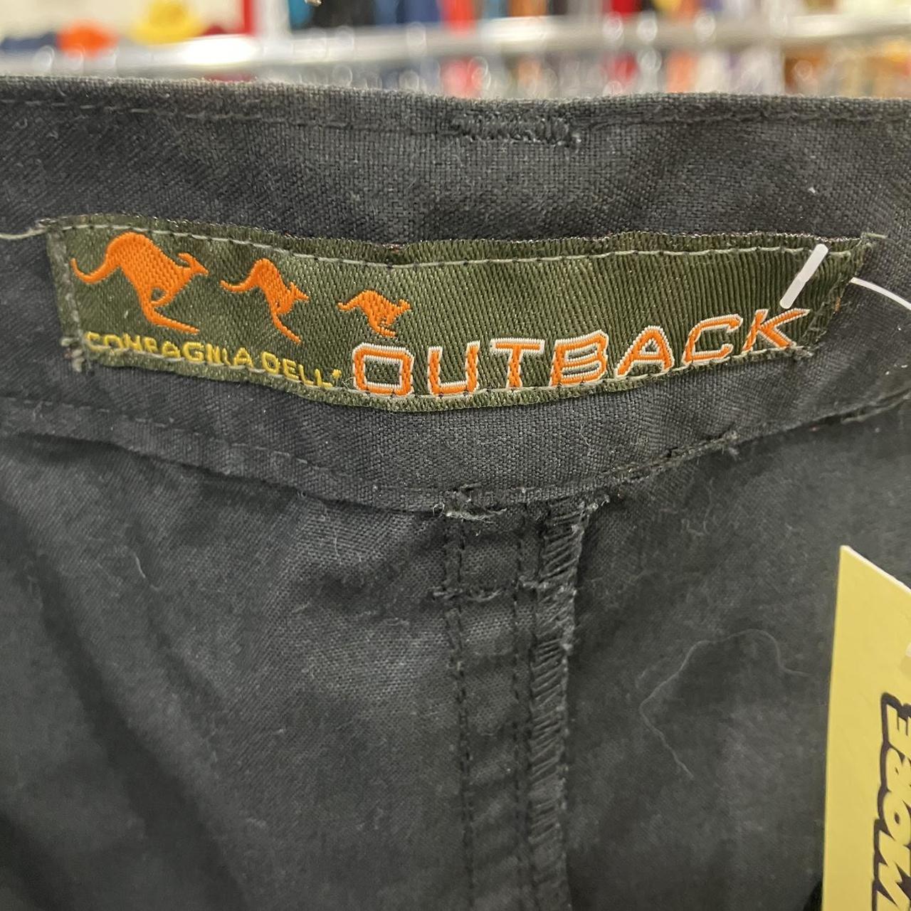 Close-up of a label on a black garment with 'Outback' branding