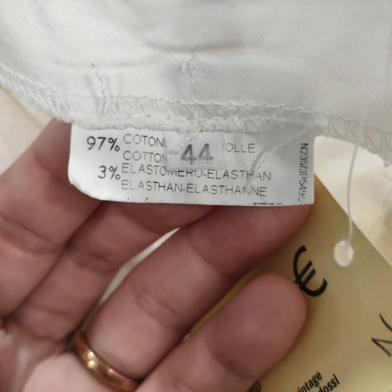 Close-up of clothing care label showing size 44, 97% cotton, 3% elastane fabric blend