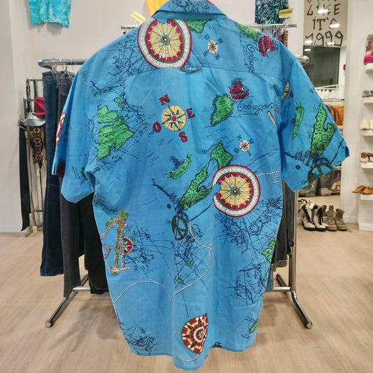 Blue short sleeve shirt with vintage map and compass print, hanging in thrift fashion store