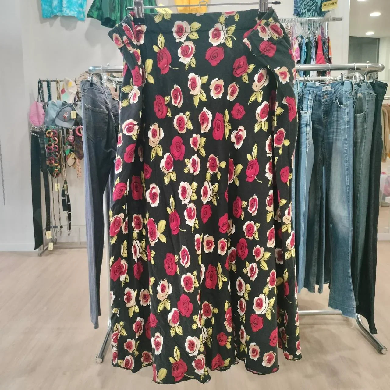 Black midi skirt with red rose floral print displayed in a sustainable fashion store