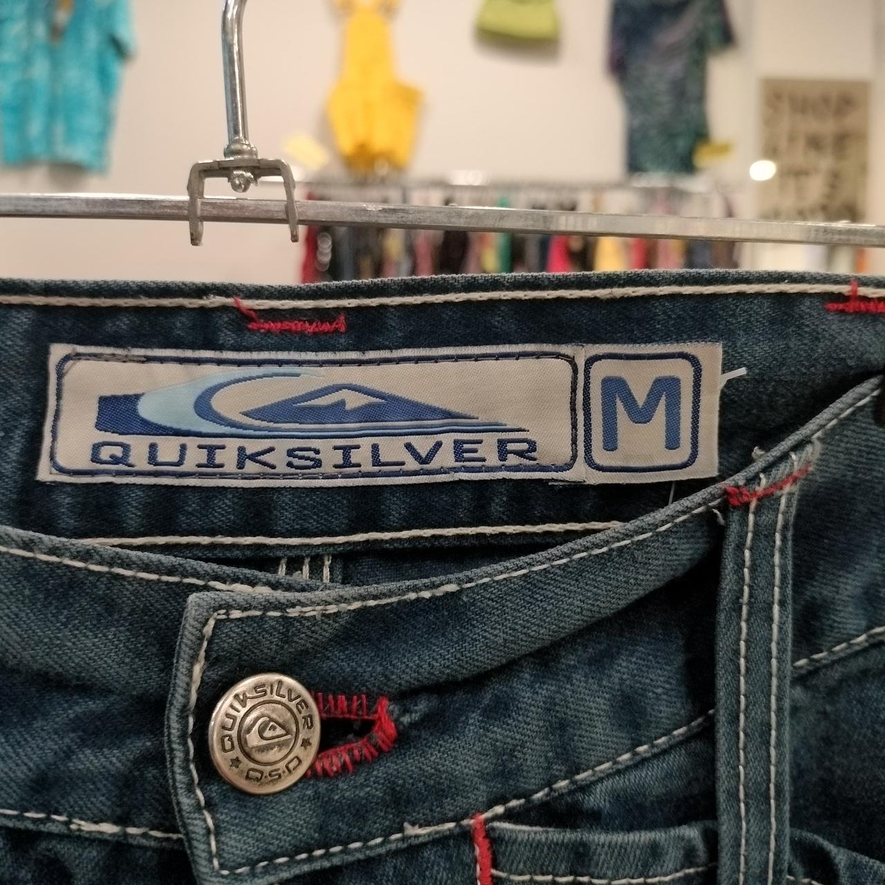 Close-up of a Quiksilver denim label on a jeans back pocket with a hanger in the background